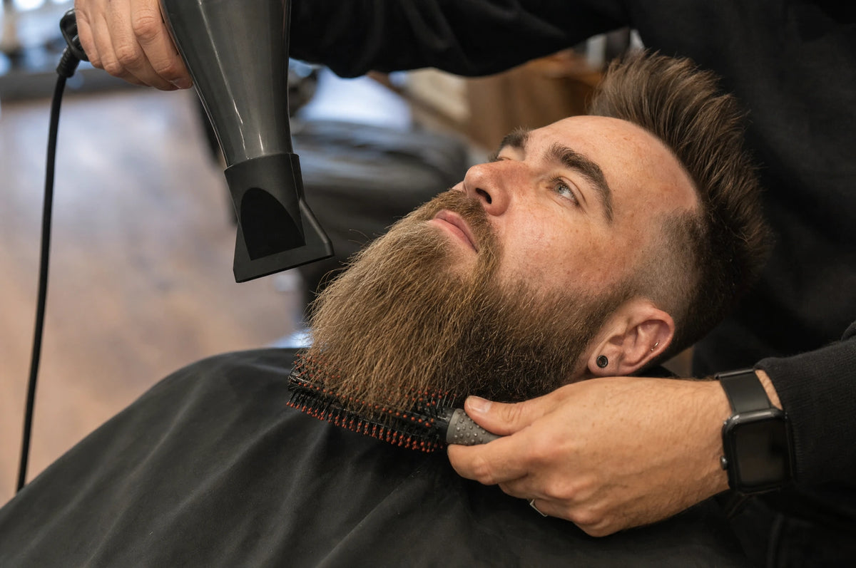 Barber blow-drying and brushing a reclining client’s long beard